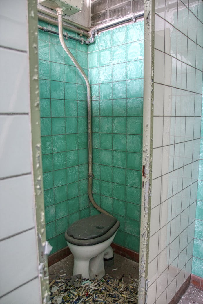 creative An abandoned restroom with green tiles and broken fixtures, revealing signs of decay.